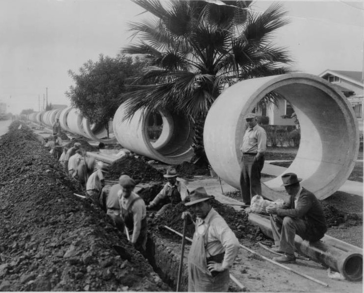 Slauson Avenue storm drain construction. Men use shovels to dig a deep trench along 69th Street, 1934