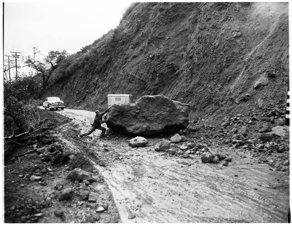 Landslides still were a problem for motorists like this man attempting to move a boulder near Pacific Coast Highway, 1952