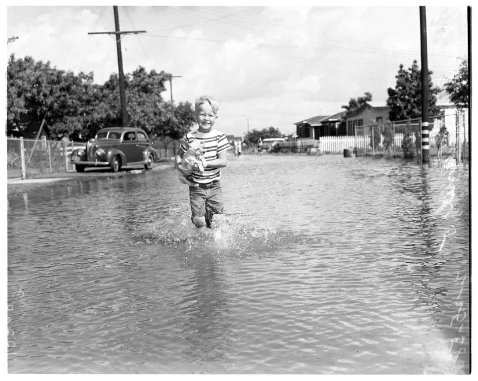 Still some people found time to enjoy the extra water like this boy with his puppy on a flooded street in Pico Rivera, 1958