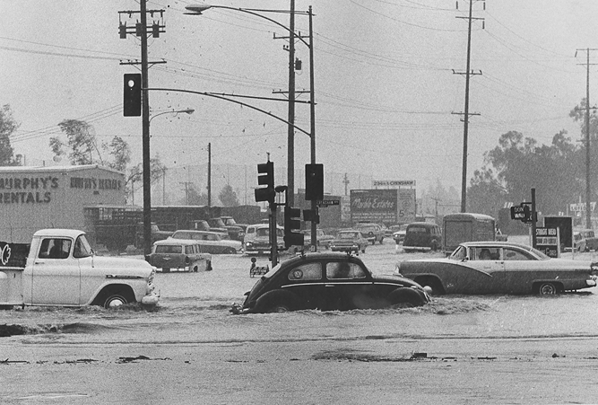 Autos navigate floodwaters on Crenshaw Boulevard in Torrance during a December storm, 1965