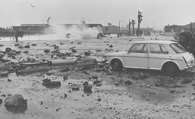 Debris-littered parking lot at King Harbor in Redondo Beach after storm-driven waves receded, 1983